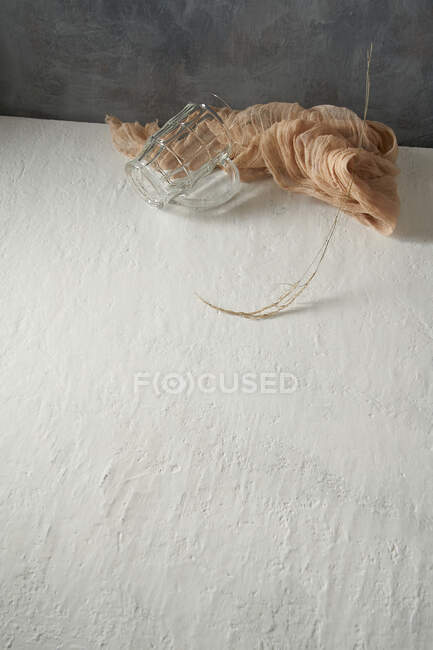 Copo de vidro e pano colocado com galho de árvore no fundo bege e cinza — Fotografia de Stock