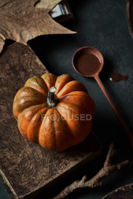 From above appetizing ripe orange pumpkin on wooden tables with dry stick leaves and spoon — Stock Photo