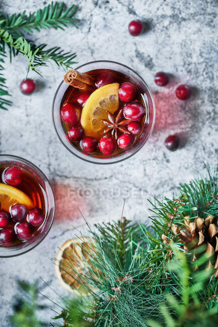 Vista dall'alto di bicchieri con mirtilli rossi con limone accanto alla decorazione natalizia — Foto stock