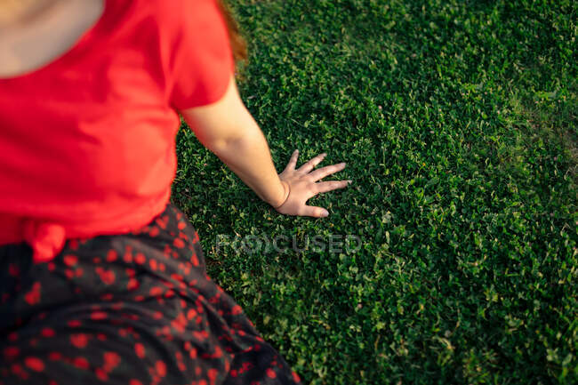 Colheita Tranquilo fêmea sentado na grama no prado no parque e desfrutar do pôr do sol no verão — Fotografia de Stock