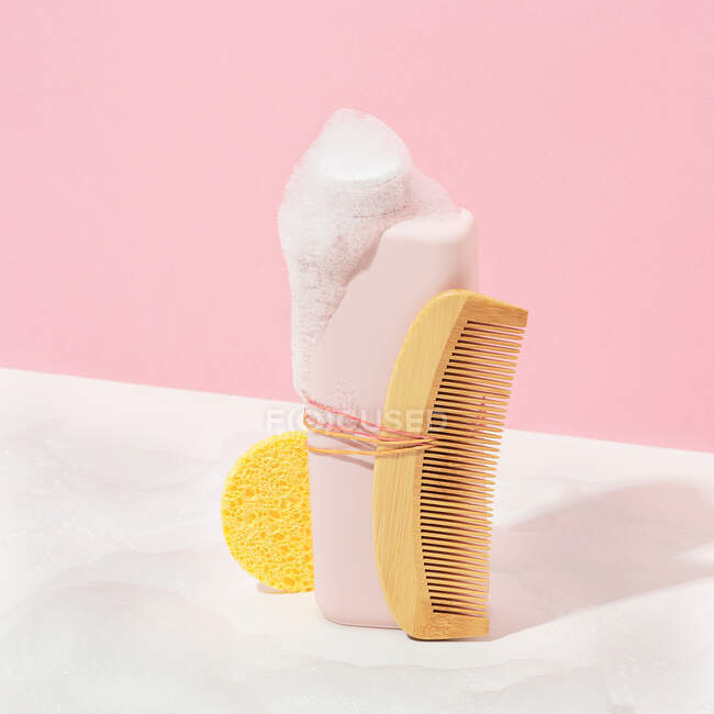 From above still life of a bottle of bath gel with a comb and a sponge ready to be used — Stock Photo