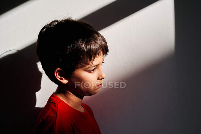 Vista lateral de triste niño preadolescente solitario indefenso con moretones en la cara que sufren de violencia doméstica - foto de stock