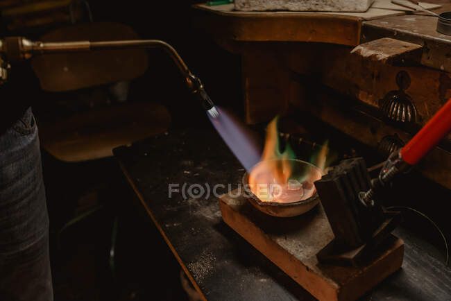 Невпізнаваний ювелір плавить метал для ювелірних виробів з вибуховим факелом стоячи біля майстерні. — стокове фото