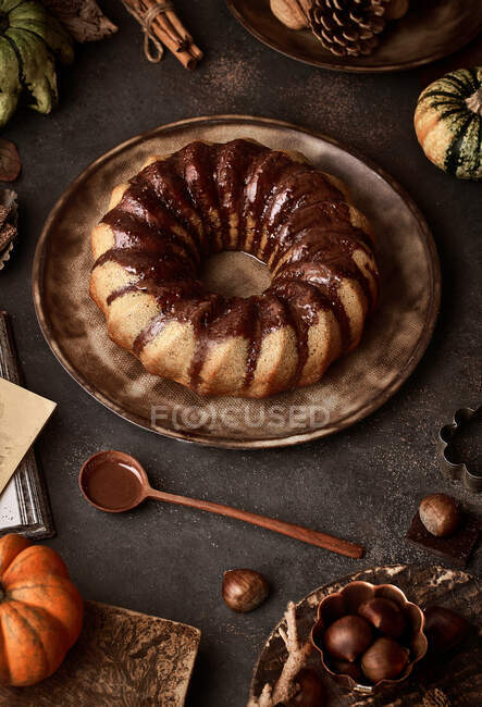 From above tasty appetizing pumpkin cake with chocolate cream on table decorated with autumn vegetables — Stock Photo