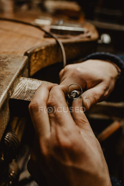 Mani di orafo maschio anonimo utilizzando strumento manuale per modellare anello metallico in officina — Foto stock
