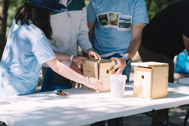 Team of activists constructing wooden nesting boxes while gathering together in summer park — Stock Photo