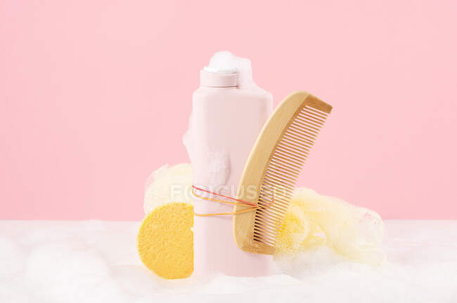 Front view of still life of a bottle of bath gel with a comb and a sponge ready to be used — Stock Photo