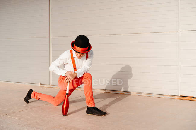 Side view of skilled young male circus performer juggling with club on modern building — Stock Photo