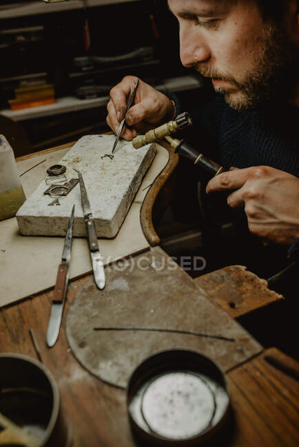 Чоловічий золотошукач використовує ручний інструмент для формування металевого кільця в майстерні — стокове фото