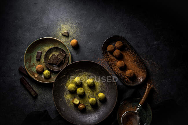 Overhead big plate with green truffle Matcha and plate with brown truffles balls with powder and strainer and chocolate pieces — Stock Photo