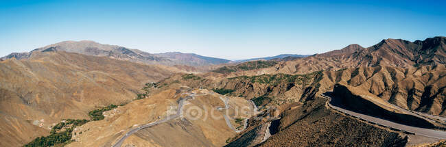 D'en haut de la route sinueuse asphaltée vide sur de puissantes collines brunes par une journée ensoleillée au Maroc — Photo de stock
