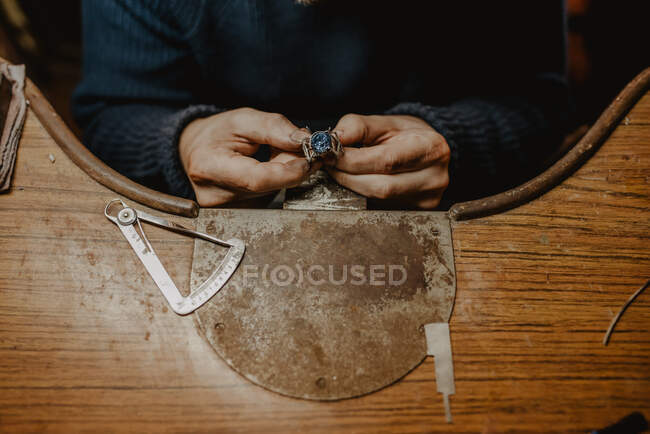 Bijoutier anonyme tenant la bague inachevée dans des mains sales et vérifiant la qualité dans l'atelier — Photo de stock