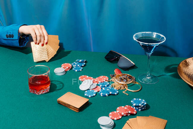 Кадрирование неузнаваемая женщина с картами и фишками играть в покер, сидя за зеленым столом — стоковое фото