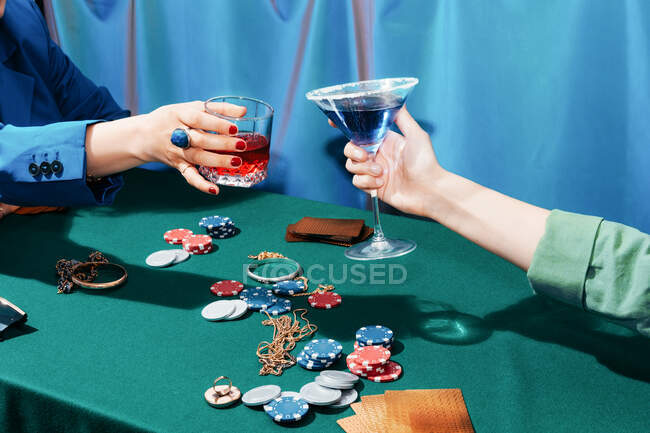 Ritaglia amiche irriconoscibili giocando a poker e tintinnando bicchieri di cocktail alcolici mentre diverti di notte — Foto stock