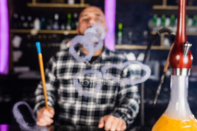 Uomo che fuma narghilè tradizionale in un night club — Foto stock