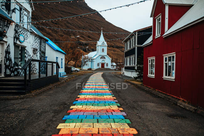 Вулиця з яскравою цеглою між будівлями села біля собору та гори — стокове фото