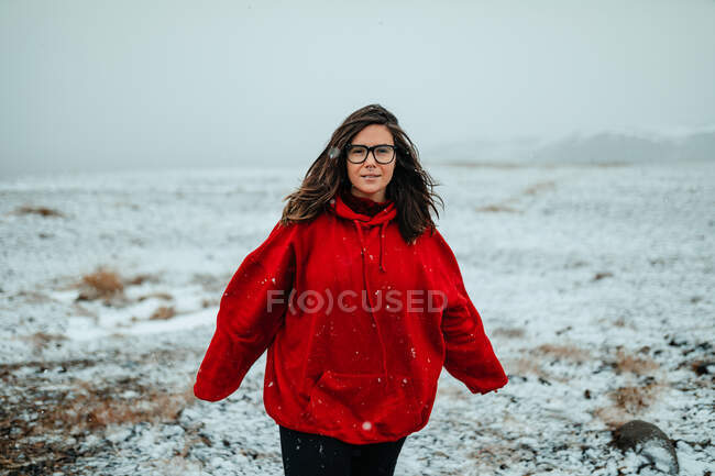 Giovane turista felice in occhiali con piercing guardando la fotocamera tra terreno deserto nella neve — Foto stock