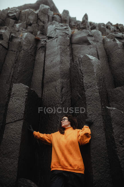 Young tourist in eyeglasses posing near high black stone wall — Stock Photo