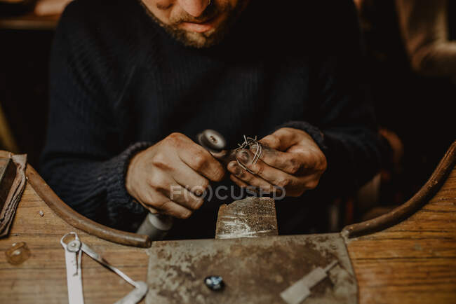 Ювелір, використовуючи професійну полірувальну машину на робочому місці під час виготовлення металевого кільця в майстерні. — стокове фото