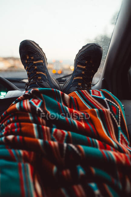 Gambe raccolto di turista coperto con coperta in una macchina — Foto stock