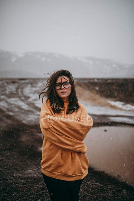 Junger fröhlicher Tourist in Brille mit stechenden Blicken in die Kamera zwischen menschenleerem Boden im Schnee — Stockfoto