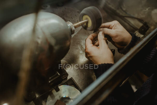 Hands of anonymous male goldsmith using manual tool to shape metal ring in workshop — Stock Photo