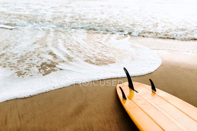 Зверху дошка для серфінгу на піску з морськими хвилями на фоні — стокове фото