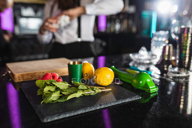 Мята, лимоны, малина и посуда на барном столе для приготовления коктейлей — стоковое фото