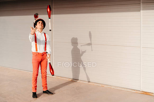 Skilled young male circus performer juggling with club on modern building — Stock Photo