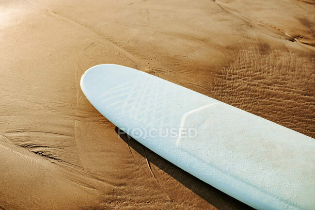 Зверху дошка для серфінгу на піску з морськими хвилями на фоні — стокове фото