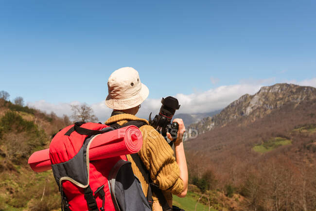 Rückansicht einer anonymen Backpackerin, die während der Reise bergige Landschaft fotografiert — Stockfoto