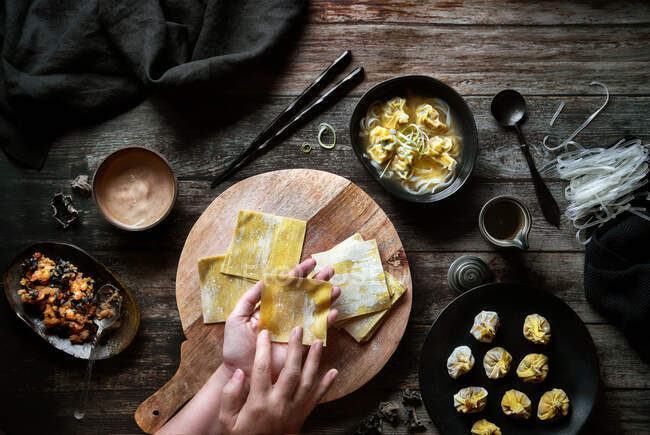 Top view of anonymous woman preparing wonton soup on a wooden table — Stock Photo