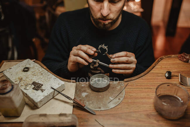 Joalheiro anônimo segurando anel inacabado em mãos sujas e verificando a qualidade na oficina — Fotografia de Stock