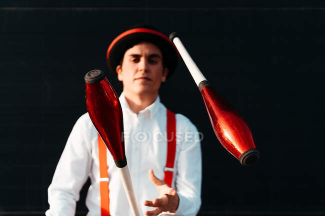 Geübte junge männliche Zirkusartisten jonglieren mit Schläger auf modernem Gebäude — Stockfoto