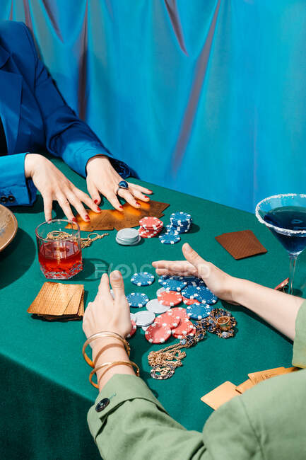 Посев неузнаваемых женщин-друзей, сидящих за зеленым столом с картами и фишками для покера во время азартных игр — стоковое фото