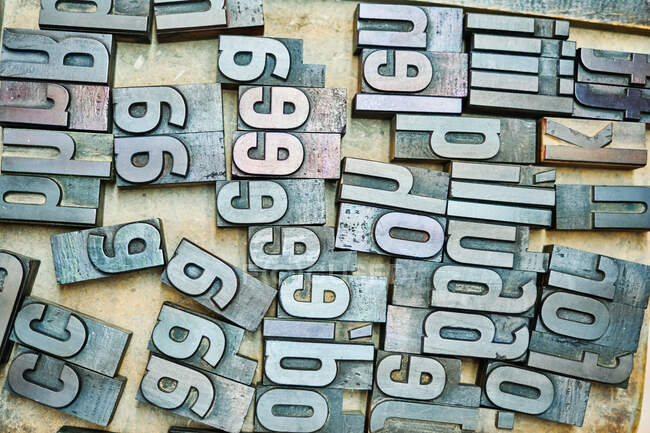 Draufsicht auf eine Reihe schäbiger Buchstaben aus Metall, die in einer Holzkiste in Typografie platziert sind — Stockfoto