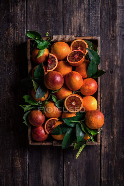 Top view a tray with sanguine and green leaves on a wooden table — Stock Photo