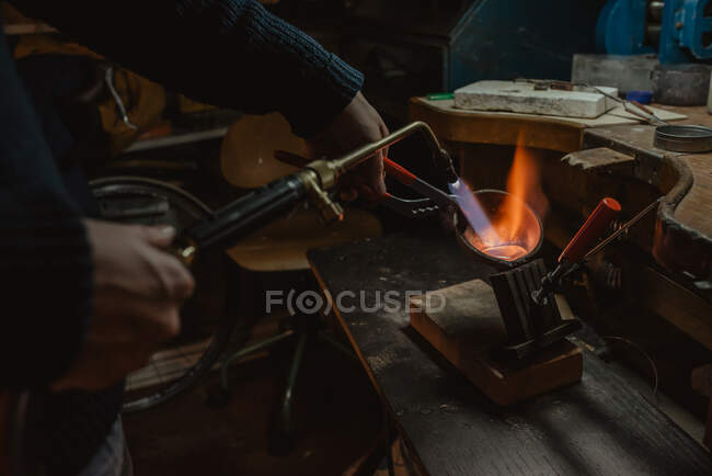 Oreficeria irriconoscibile metallo fuso per gioielli con fiamma ossidrica mentre in piedi vicino al banco da lavoro in officina — Foto stock