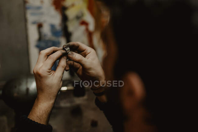 Gioielliere irriconoscibile che utilizza una lucidatrice professionale sul banco da lavoro mentre realizza un anello metallico in officina — Foto stock