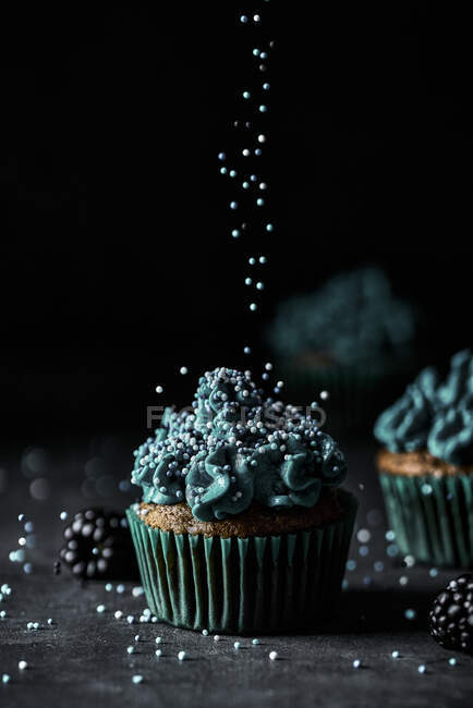 Fresco bel muffin al forno festivo con gustosa crema pasticcera blu e spruzza durante la decorazione — Foto stock