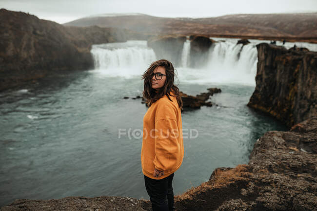 Voltar vista mulher entre terras selvagens com cachoeira — Fotografia de Stock