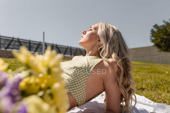 Side view of female with closed eyes enjoying sunny day on grassy meadow in countryside — Stock Photo