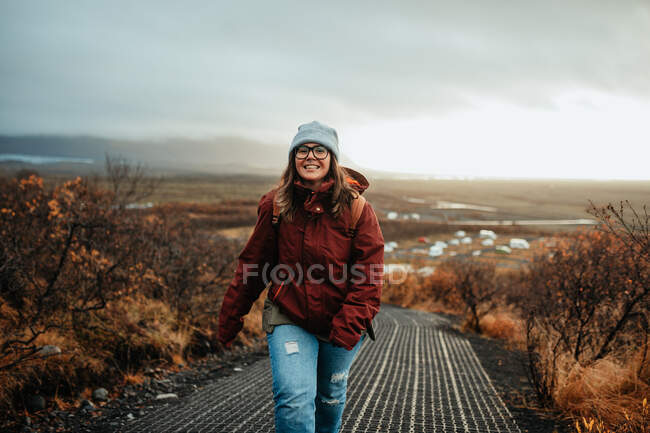 Молоді щасливі туристи взимку ходять по лісовій дорозі та хмарному небу. — стокове фото