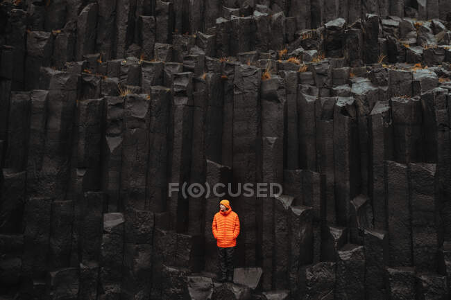 Young tourist in eyeglasses posing near high black stone wall — Stock Photo