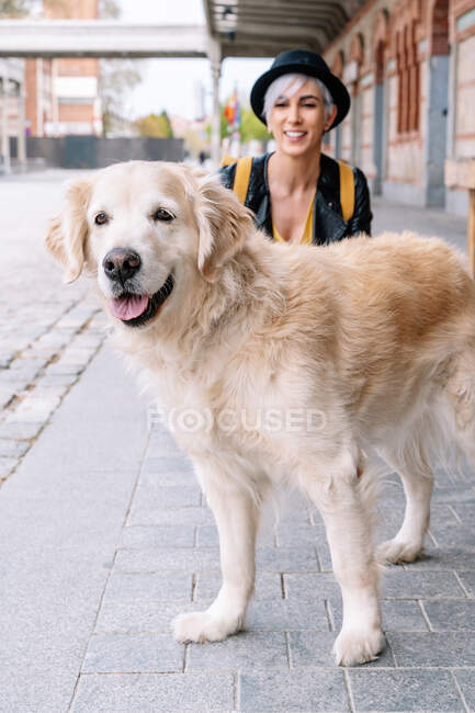 Blond female with purebred dog crouching on urban pavement — Stock Photo