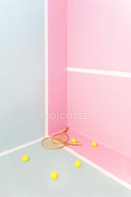 Retro wooden tennis rackets and yellow balls placed in corner of studio in trendy pastel colors — Stock Photo