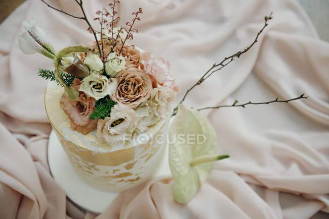 Зверху весільний торт, прикрашений квітучими трояндами і горошками ніжних пастельних кольорів рожевого скатертини. — стокове фото