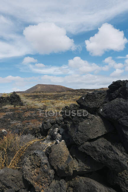 Amazing landscape of rocky terrain with mountains under blue sky on Lanzarote island — Stock Photo