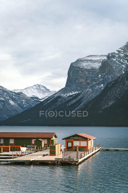 Док з пучками, що пливуть на воді озера Мінневана проти снігового гірського хребта в провінції Альберта (Канада). — стокове фото