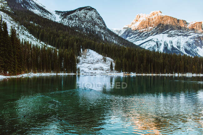 Чиста вода з мирного озера Емеральд, що відбиває сніжний гірський хребет і хмарне небо в зимовий день в Альберті (Канада). — стокове фото